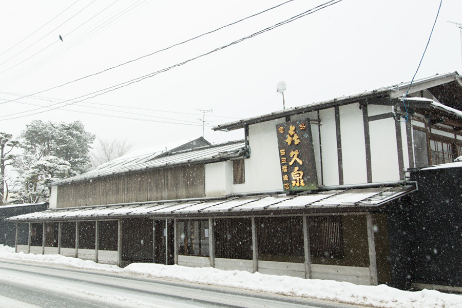 田酒の瓶とおちょこ、純米酒の透明な液体が映る写真